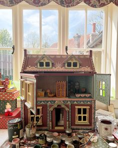 a doll house sitting on top of a table in front of a window filled with toys