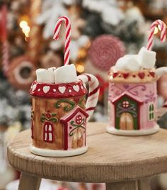 two coffee mugs decorated with candy canes and gingerbread houses are sitting on a table