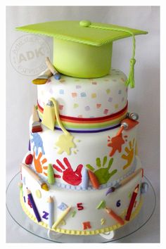 a multi layer cake decorated with hand prints and a green graduation cap