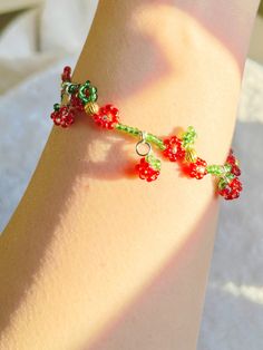 a close up of a person's foot wearing a bracelet with red and green beads