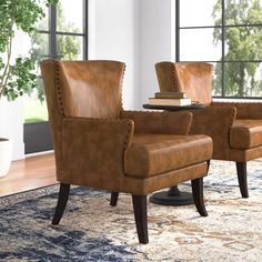 two brown leather chairs sitting on top of a rug