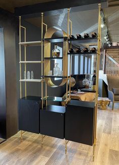 a black and gold display case with wine glasses on it's shelves in a living room