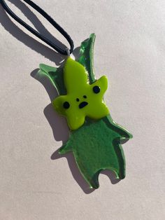 a green ceramic ornament hanging from a black cord on a white table top