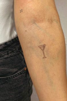 a woman with a small tattoo on her arm holding a drink in it's hand