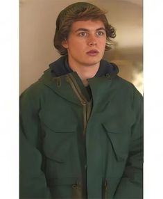 a young man in a green jacket looking at the camera