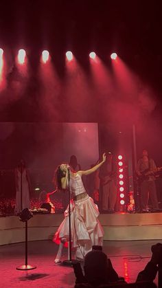 a woman in a white dress is on stage