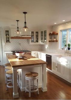 a large kitchen with white cabinets and wooden counter tops, two stools at the island