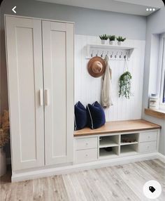 a room with some white cupboards and plants on the wall next to a bench