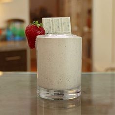 a drink with a strawberry on the top and a bar in the middle sitting on a counter