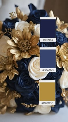 a blue and gold wedding bouquet with white roses, navy blue flowers and gold leaves