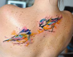 two birds painted on the back of a woman's upper back shoulder and neck