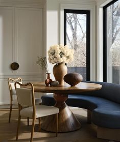 a table with flowers in a vase on top of it next to two chairs and a couch