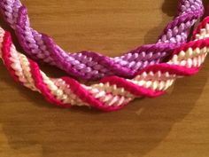 three braided bracelets sitting on top of a wooden table