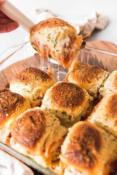 a person dipping cheese on top of rolls in a baking dish with a spatula