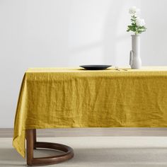 a table with a yellow cloth on it and a white flower in a vase next to it