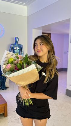 a woman holding a bouquet of flowers in front of a mannequin behind her