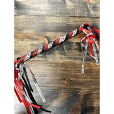 a red, white and black ribbon tied to a wooden pole on top of a wood floor