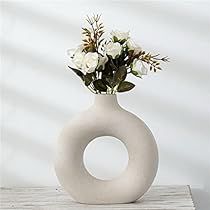 a white vase with flowers in it sitting on a table