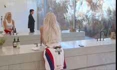 a woman standing in front of a counter with bottles on it