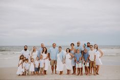 a large group of people standing on top of a sandy beach next to the ocean