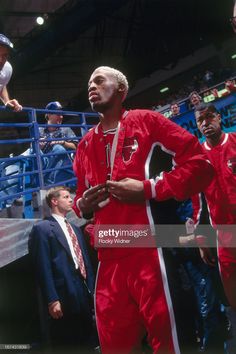 professional basketball player in red uniform standing on the sidelines during a game with his team