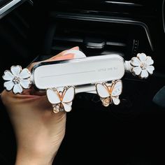 a woman is holding up some white flowers in her hand while she's driving