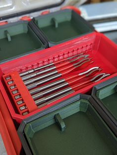 there are many tools in the toolbox and it is red with green trays