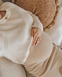 a woman laying on top of a couch next to a teddy bear wearing a sweater