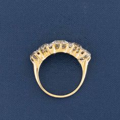 a gold ring with five small diamonds on the top and bottom, sitting on a blue surface