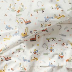 a white sheet with construction vehicles and trucks printed on it, next to a pillow