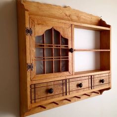 a wooden cabinet with glass doors and drawers on the front, against a white wall