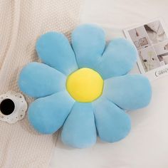 a blue flower shaped pillow sitting on top of a bed