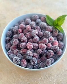 a bowl filled with powdered berries and a green leaf on top of the bowl