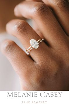 a woman's hand wearing a gold ring with a white flower on the side