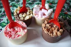 four different desserts on a white plate with red spoons and candy toppings