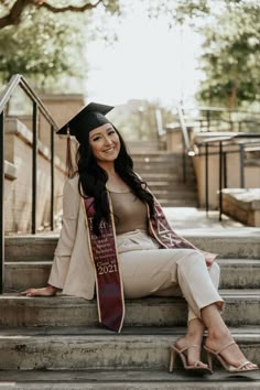 a woman sitting on some steps wearing a graduation cap and gown with her name written on it