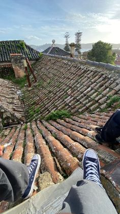 two people sitting on the roof of an old building with moss growing all over them