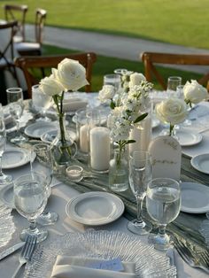 the table is set with white flowers and place settings for two people to sit at