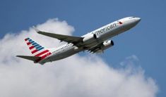 an american airlines plane flying in the sky with clouds behind it and blue skies above