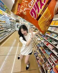 a woman is standing in the aisle of a grocery store holding up a giant bag