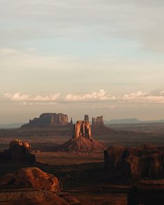 the desert is full of rock formations and mountains in the distance, with clouds overhead