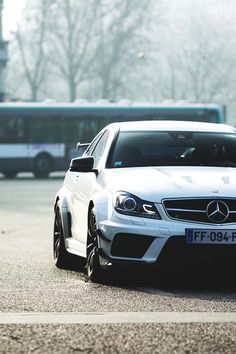 a white car parked in front of a bus