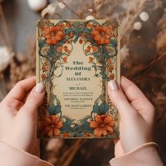 a person holding up a wedding card in front of some dried flowers and branches with the words'the wedding of alexandria'written on it