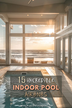 An indoor pool in a luxurious Airbnb with floor-to-ceiling windows overlooking a serene beach at sunset, casting warm golden light across the modern, elegant space.