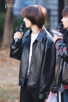 two young men standing next to each other with microphones in their hands and one wearing a black leather jacket