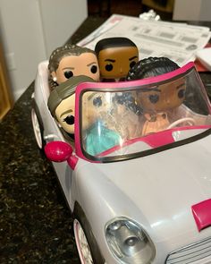 a toy car with three people in it sitting on a counter next to some papers