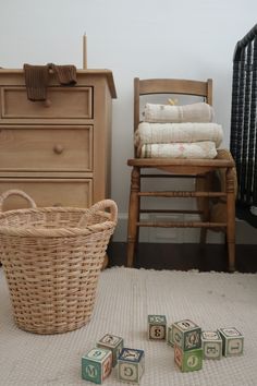 a wicker basket sitting on top of a rug next to wooden blocks and a chair