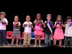 a group of children standing on top of a stage with microphones in their hands