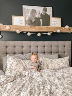 a small child laying on top of a bed in a room with pictures above it