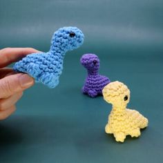 two crocheted toy animals being held by someone